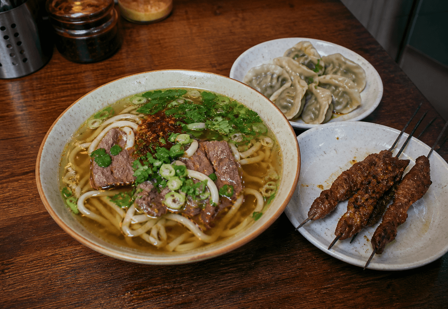A Chinese halal meal of clear-broth beef noodles, lamb skewers, and beef dumplings