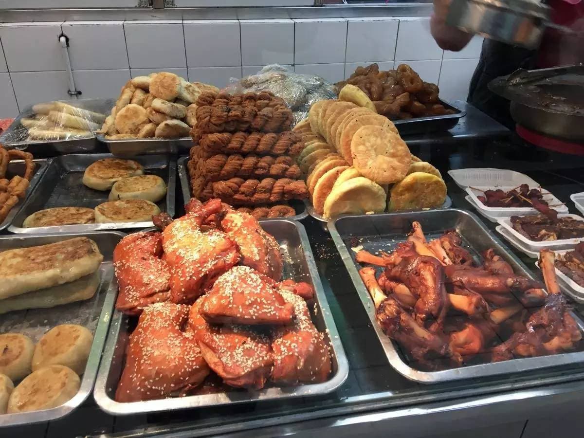 A Chinese halal street-food counter: sesame cakes, flatbreads, sanzi twists and braised bites