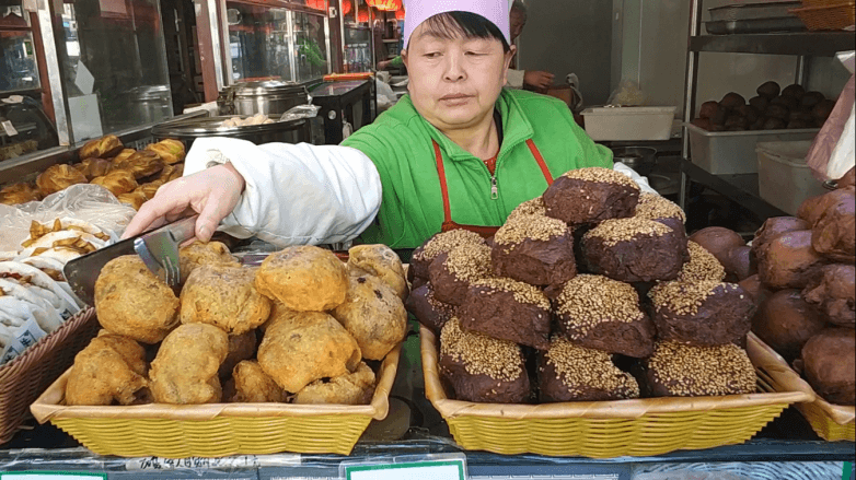 A Chinese street food stall: fried dough snacks and sesame-coated cakes