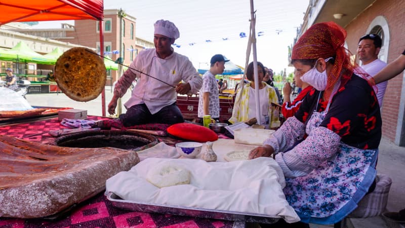 A Uyghur baker hooking a fresh naan out of the tandoor