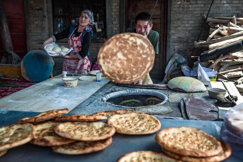 Freshly baked naan by the tandoor, with dough rounds waiting to bake