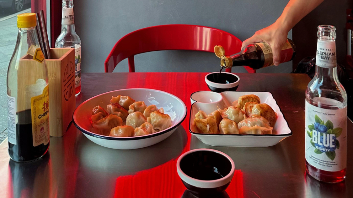 Two plates of pan-fried dumplings and dipping sauce at Little Little