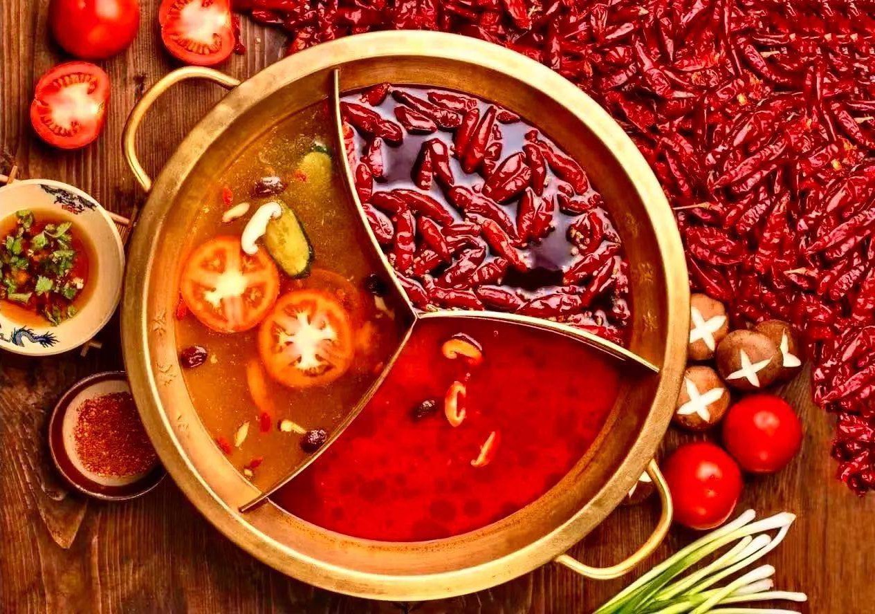 A three-section hotpot with chillies, tomatoes and other ingredients