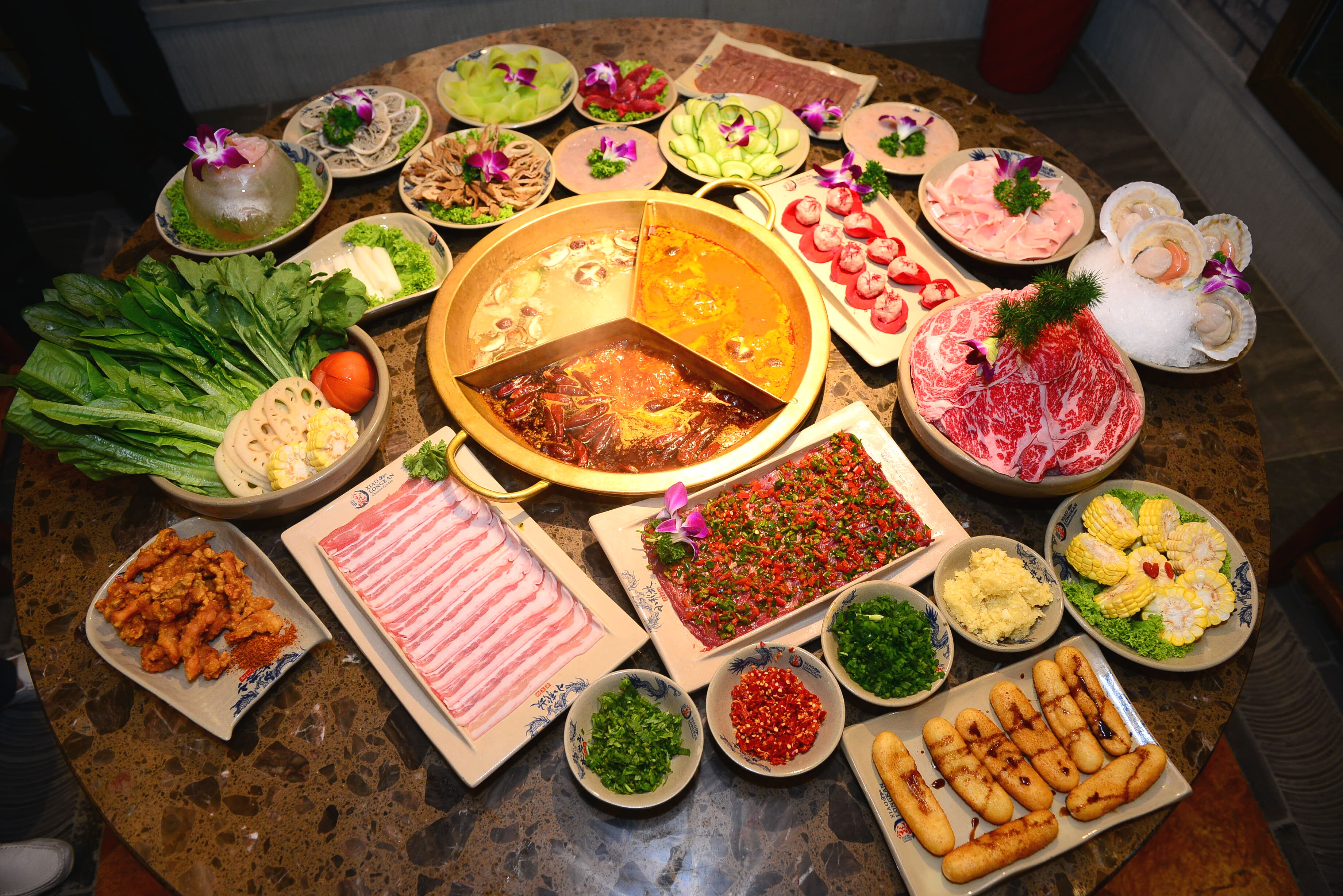 Geteilter Hotpot mit Fleisch und Gemüse auf dem Tisch